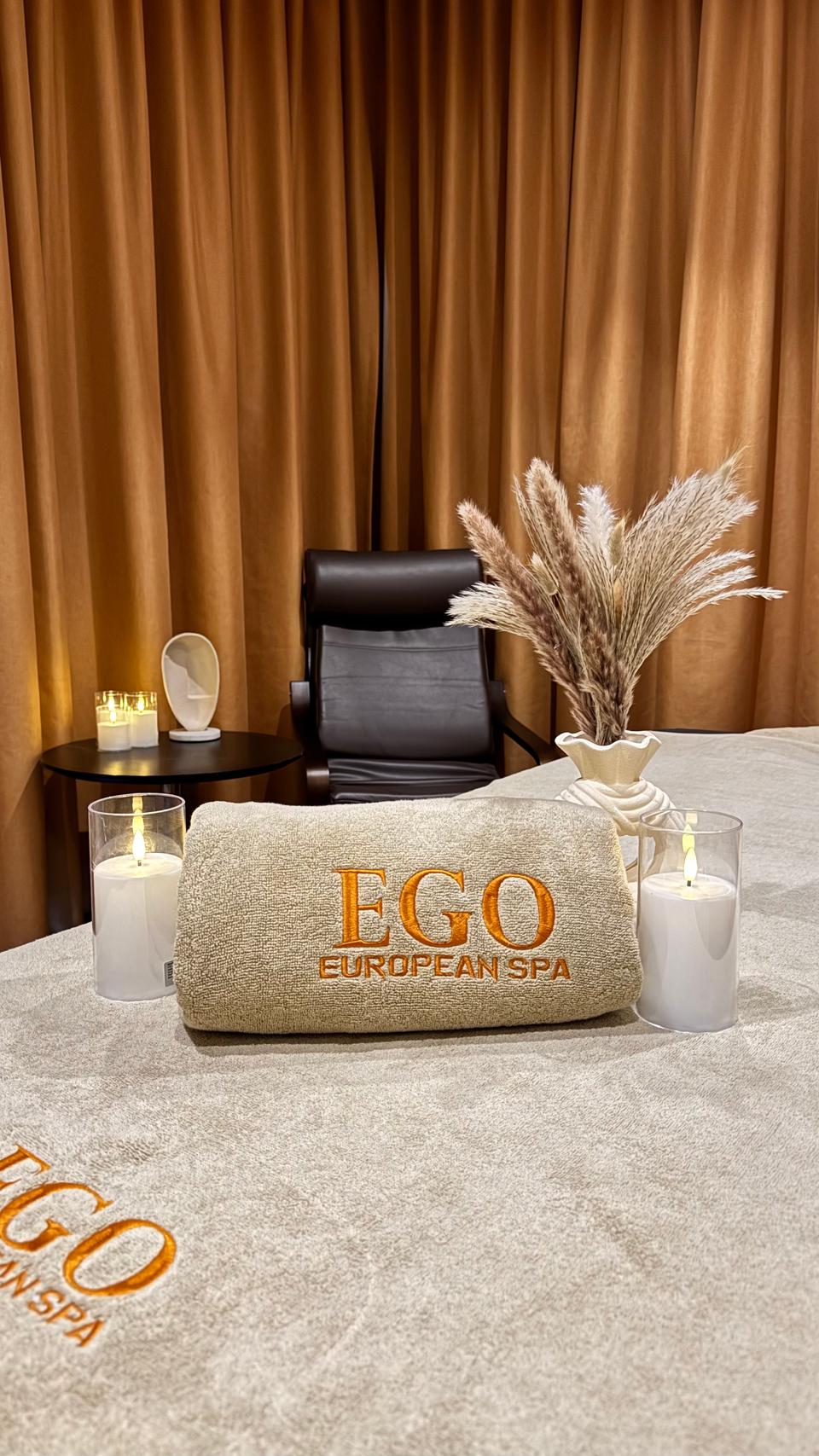 Private spa suite at Ego European Spa Dubai with EGO branded towel, leather recliner, candles, and pampas grass