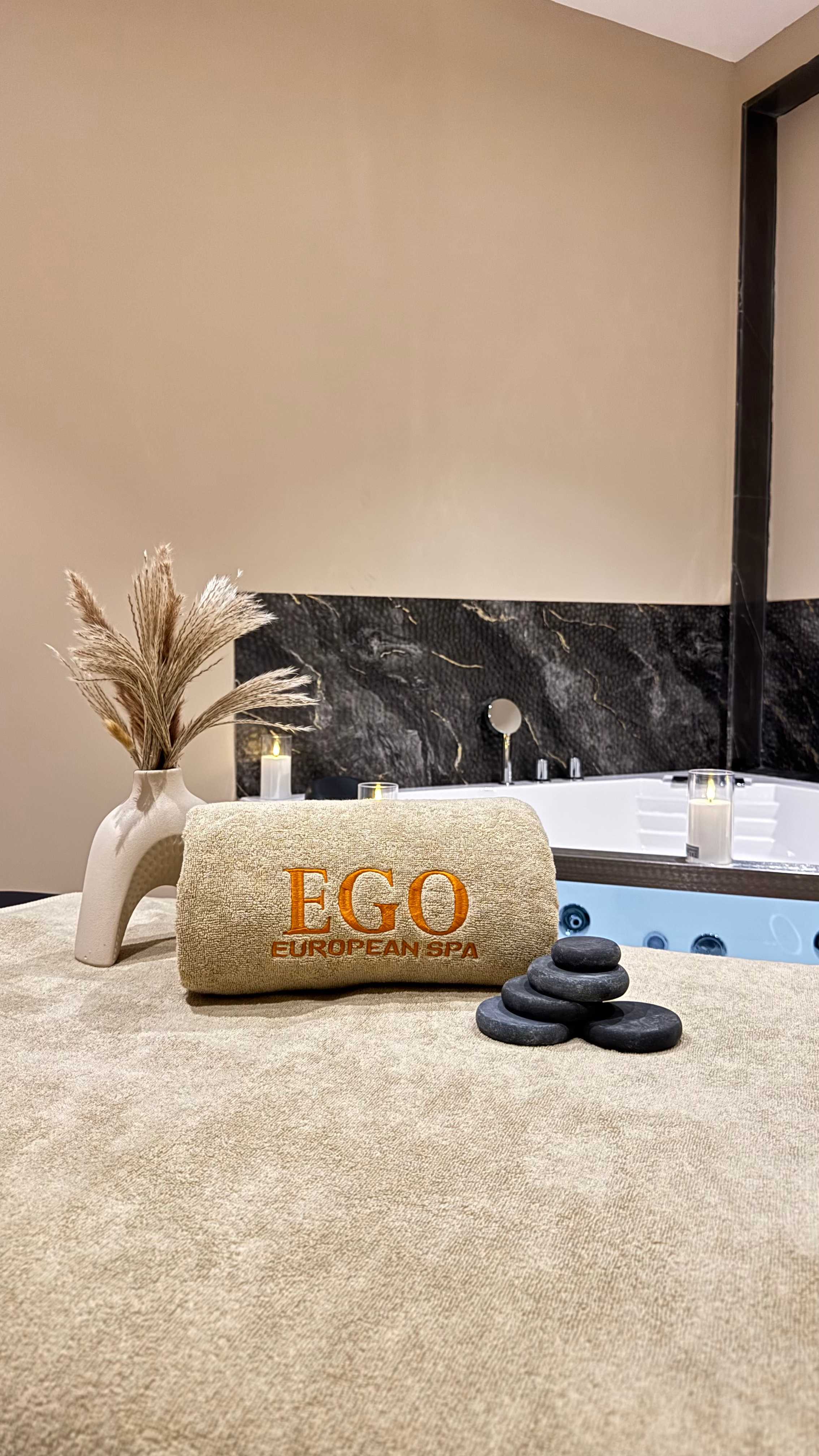 Hot stone massage setup at Ego European Spa Dubai — black basalt stones stacked on a treatment table with EGO branded towel